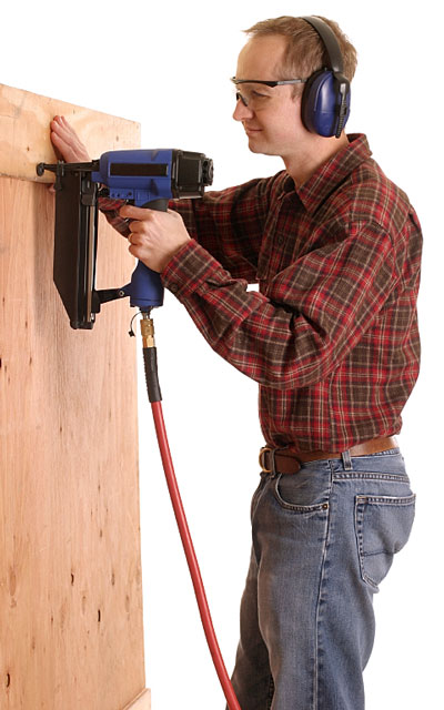 worker using an air-powered nail gun